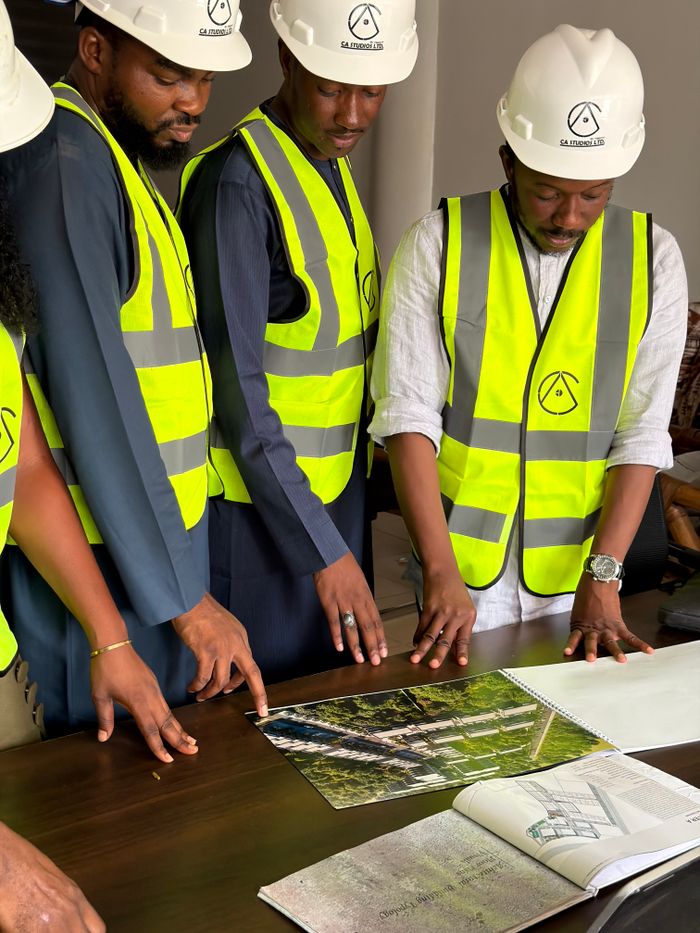 Group of engineers and architects examine building plans with safety gear.