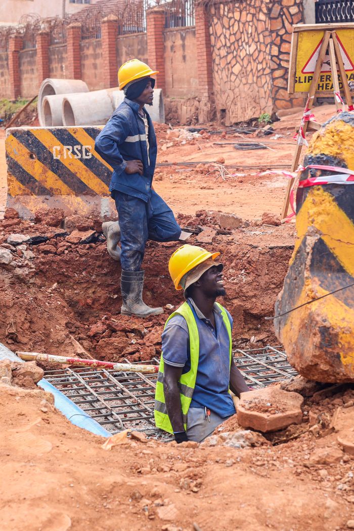 Construction workers at a site in Kampala, Uganda, engaged in excavation and building tasks.